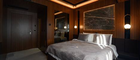 A modern bedroom with a large bed, wooden paneling, a marble accent wall, and pendant lighting.