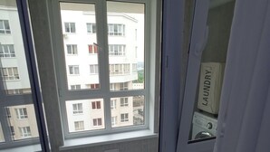 Blick vom Balkon mit Fenster auf ein Mehrstöckhaus mit Balkonen.