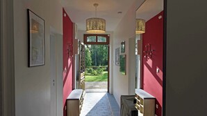 A hallway with red walls, patterned floor tiles, and a view of greenery outside. - Nature, peace and relaxation at the Péziers mill (Treigny-Perreuse-Sainte-Colombe)