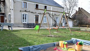 A sandy play area with a swing set and a wooden bench. - Nature, peace and relaxation at the Péziers mill (Treigny-Perreuse-Sainte-Colombe)