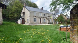 A two-story house with a sloped roof, a front porch, and a garden with yellow flowers. - Nature, peace and relaxation at the Péziers mill (Treigny-Perreuse-Sainte-Colombe)