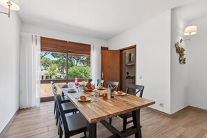 Ein Essbereich mit Holztisch, Stühlen und Blick auf Grünfläche.