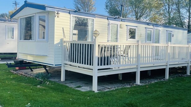 Une maison mobile dotée d’une terrasse clôturée, d’un porche et d’une façade avec des fenêtres.