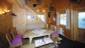 A cozy cabin interior with a wooden dining table, cushioned chairs, and a fireplace. - Truckshutte Holiday Home (Mayrhofen)