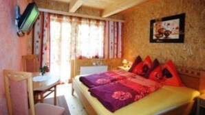 A cozy room with a bed, a desk, and a television mounted on the wall. - Truckshutte Holiday Home (Mayrhofen)