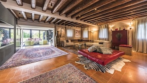 A spacious living area with a red leather sofa, patterned rugs, and a wooden ceiling. - Romantic escape in luxury Italian villa, (Veneto)