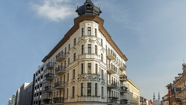 A corner building with ornate architectural details, multiple balconies, and a prominent tower. - Homewell Apartments Żelazko (Poznan)