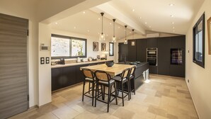 A modern kitchen with a large island, dark cabinetry, and pendant lighting.