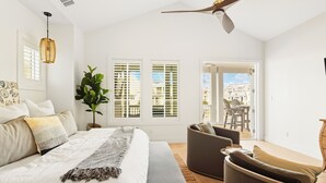 A bedroom with a bed, bedside tables, a ceiling fan, and a view of the outside. - Inviting Beach Home w/ Cinnamon Shore South Style & Amenities (Port Aransas)