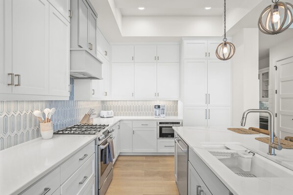 A modern kitchen with white cabinetry, a built-in oven, a coffee maker, and a sink with a modern faucet.