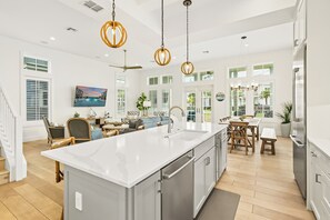 A spacious kitchen with a large island, stainless steel appliances, and pendant lighting.
