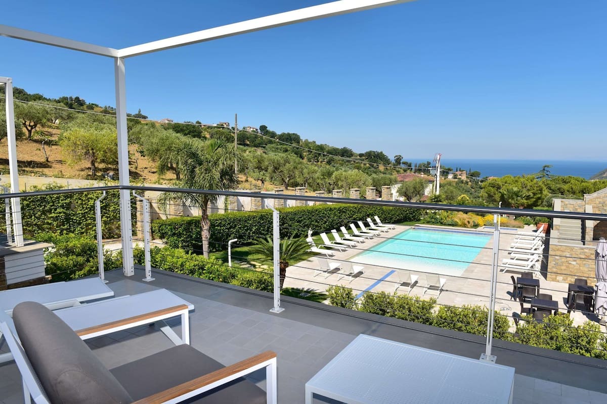 A rooftop terrace with a pool, lounge chairs, and a view of the sea.
