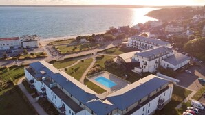 Ett hotell vid kusten med flera byggnader, en swimmingpool och utsikt över havet.