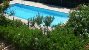 A rectangular swimming pool surrounded by lush greenery and a fence.