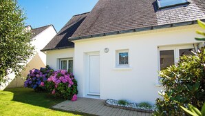 Een wit huis met een donker dak, een voordeur en een klein raam.