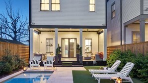A two-story house with a covered patio, a swimming pool, and outdoor seating. - Deluxe Modern Home, Heated Pool & Game Room (New Orleans)