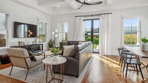 A spacious living room with a sofa, a coffee table, and a TV mounted on the wall. - Deluxe Modern Home, Heated Pool & Game Room (New Orleans)
