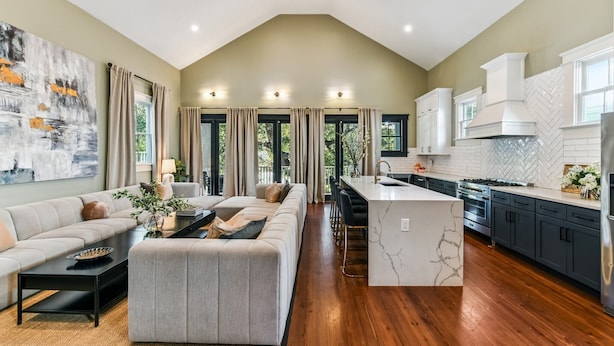 A spacious living area with a high ceiling, a kitchen with modern appliances, and a dining area. - LGD Designer Dream Condo | Heated Pool (New Orleans)