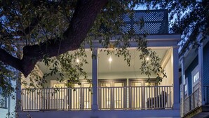A two-story house with a pool, outdoor seating, and a staircase leading to the entrance. - LGD Designer Dream Condo | Heated Pool (New Orleans)
