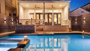A swimming pool with a covered patio area, outdoor seating, and a staircase leading to a second level.