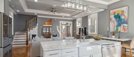 A modern kitchen with a large island, white cabinetry, and a ceiling fan.