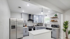 A modern kitchen with stainless steel appliances, grey cabinets, and a central island.