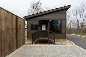 A small, modern building with a wooden deck and a staircase leading to a door. - Walk2DowntownPF/GasFirepit/Waterfront (Pigeon Forge)
