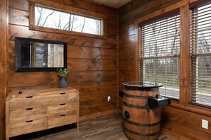 Un interior de madera con un aparador, un espejo y un barril.