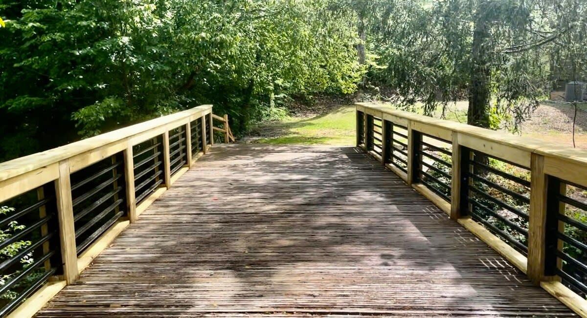 A wooden bridge with railings, surrounded by trees.