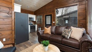 A cozy cabin interior with a brown leather sofa, a dining area, and a kitchen. - Walk2DowntownPF/GasFirepit/Waterfront (Pigeon Forge)