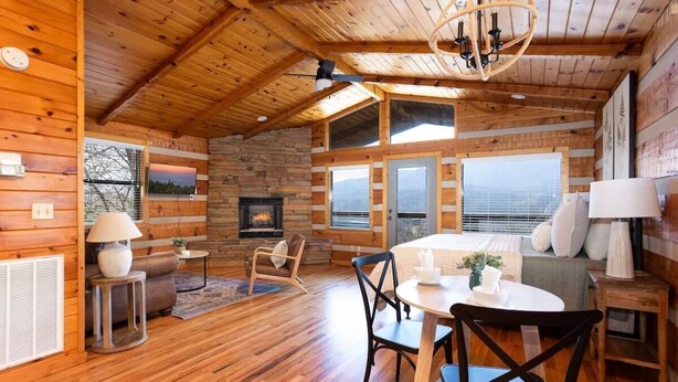 A log cabin interior with a dining area, fireplace, and large windows. - Big Mt. LeConte Views/Gatlinburg (Gatlinburg)