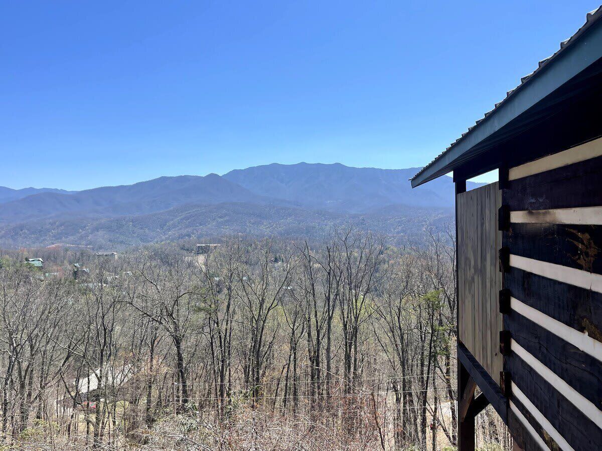 A wooden cabin with a view of a mountainous landscape.