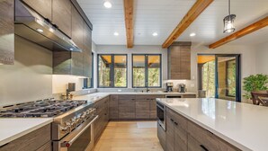 A modern kitchen with wooden cabinets, a large island, and a built-in oven.