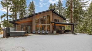 A modern log cabin with a large deck and outdoor seating area.