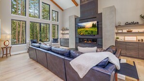 A modern living room with a large sectional sofa, a fireplace, and a television.