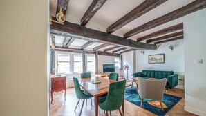 Un coin repas avec une table en bois et des chaises à revêtement vert, un canapé et un tapis bleu à motifs.