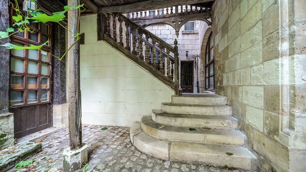 Un escalier en pierre avec une rampe en bois menant à un niveau supérieur.