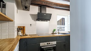 Une cuisine moderne dotée d’un plan de travail en bois, de meubles noirs, d’un four encastré et d’une hotte en acier inoxydable.