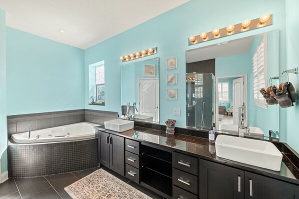 A modern bathroom with a large bathtub, two sinks, and a vanity with a mirror.