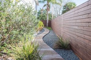 A narrow wooden pathway flanked by dense foliage and a wooden fence. - 4BR Private Pool Oasis | Sleeps 12 • Pet Friendly (St. Augustine)