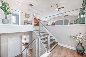 A multi-level interior with a staircase, a ceiling fan, and a vase with flowers.