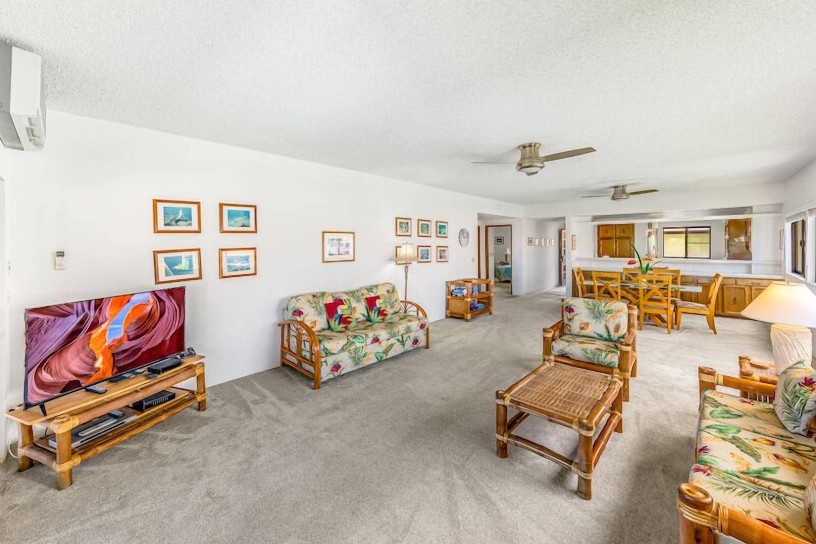 A spacious living room with a sofa, chairs, a TV, and a dining area with a table and chairs.