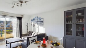 A modern living room with a dining area, a sofa, a table set with food and drinks, and a cabinet with dishes. - -LITTO- CONCARNEAU AVEC TERRASSE PROCHE COMMERCES (Concarneau)