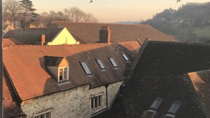 A view of a residential area with multiple buildings, including a house with a sloped roof and skylights, and another with a flat roof. - Windows Over Stroud Penthouse Apartment With Views (Stroud)