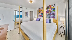 Una moderna camera d'albergo con un letto grande, vista sul mare e opere d'arte colorate alle pareti.