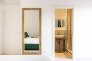 A bedroom with a bed, a mirror, and a bathroom with a sink and mirror. - Vittoria Rooms Sorrento (Sorrento)