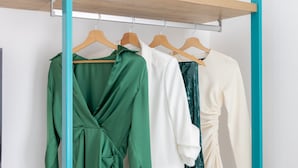 A clothing rack with three garments: a green dress, a white blouse, and a cream-colored dress. - Vittoria Rooms Sorrento (Sorrento)