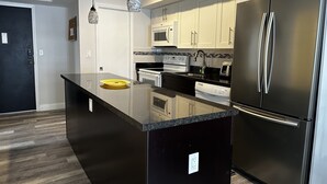 Una cocina moderna con un refrigerador de acero inoxidable, un microondas y un horno empotrado.
