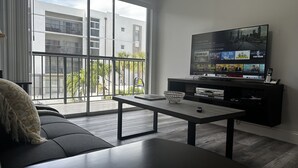 Una sala de estar moderna con un televisor grande, un sofá y una mesa de comedor.