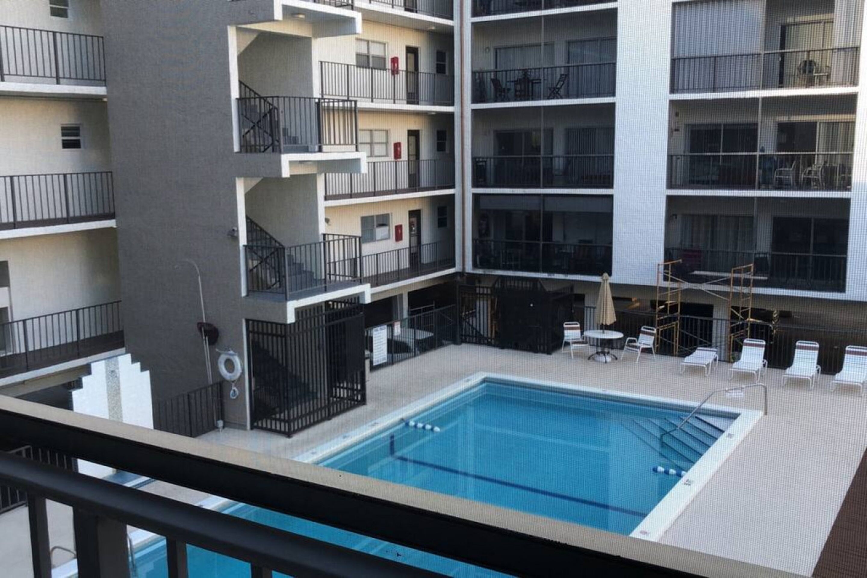 A multi-story building with a central swimming pool, balconies, and outdoor seating.